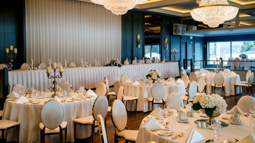 Elegant hotel ballroom with chandeliers, round tables set for a banquet, and luxurious decor, perfect for weddings.