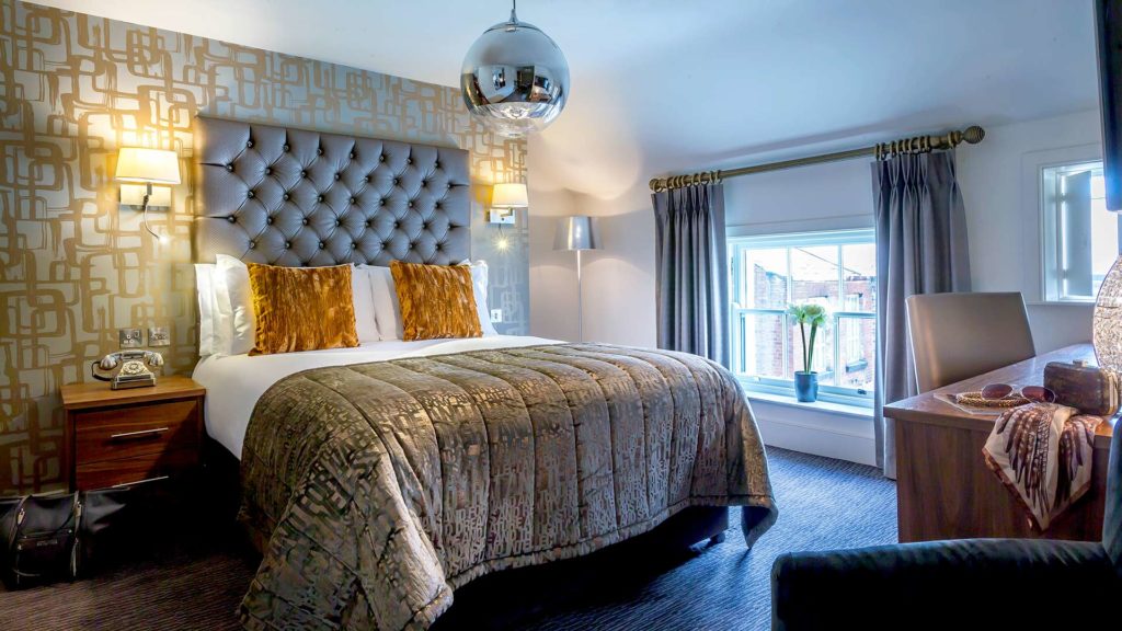 Elegant hotel room with plush bed, stylish decor, large window and soft lighting, inviting guests for a cosy stay.